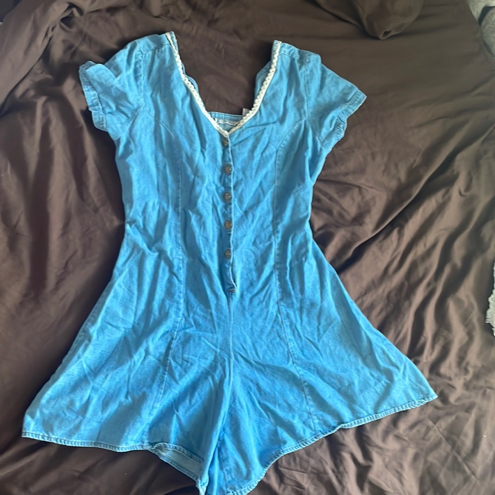 Jean romper with brass buttons and lace trimming.